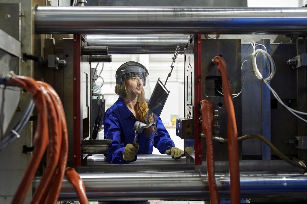 Mitarbeiterin vor einer Druckgießmaschine